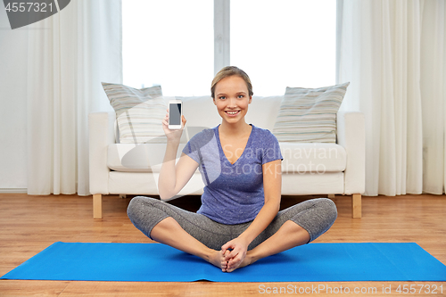 Image of woman with smartphone doing yoga at home