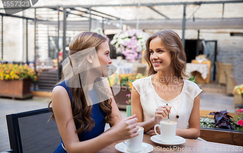 Image of smiling young women drinking coffee at street cafe