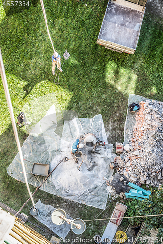 Image of Top view of authentic builder men working with shovel during concrete cement solution mortar preparation in mixer at construction site