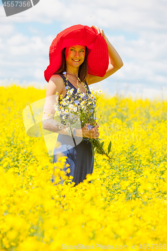 Image of beautiful white woman in a red hat and with a bouquet of wildflo