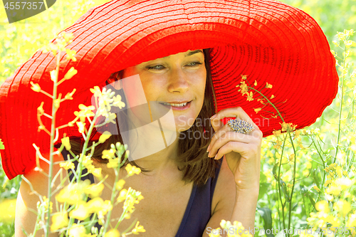 Image of pretty woman in a red hat in the field, among the flowers