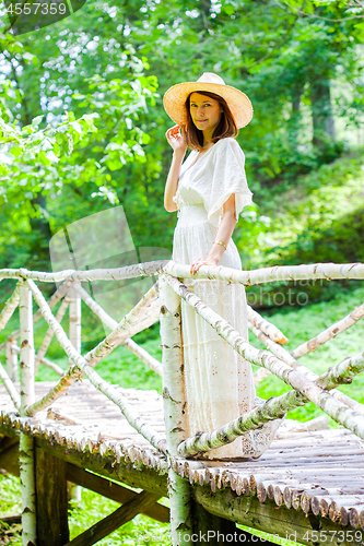 Image of beautiful middle-aged woman in a white summer dress and hat