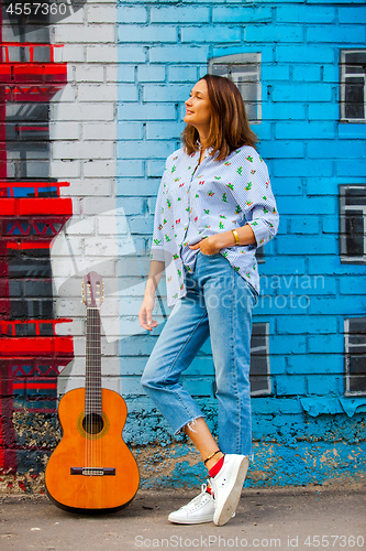 Image of Beautiful brunette in blue jeans with a guitar