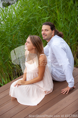 Image of Pregnancy. Happy couple resting by the lake. 