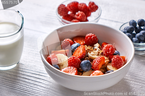 Image of Natural organic raspberry, strawberry, blueberry, nuts, oat flakes and soy milk - the set of ingredients for healthy breakfast on a wooden background