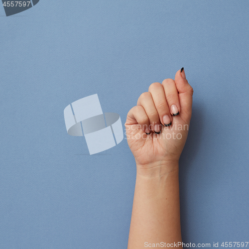 Image of Closed female hand isolated on blue background