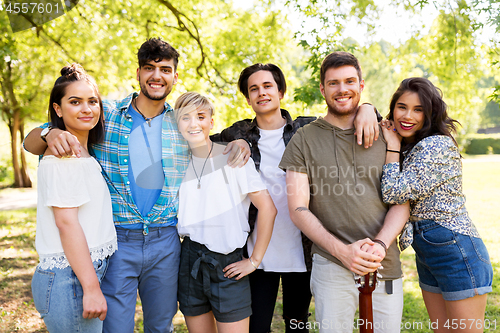 Image of happy friends with guitar at summer park