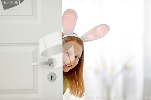 Image of happy girl with easter bunny ears peeking out door