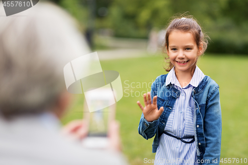 Image of little girl being photographed at summer park