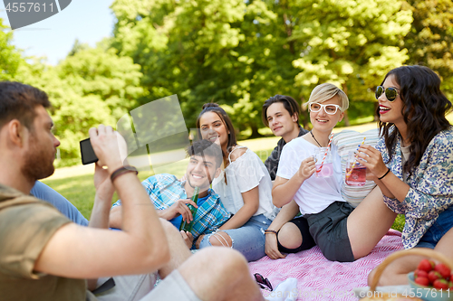 Image of guy taking picture of friends on summer picnic