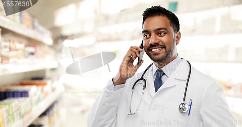 Image of smiling indian male doctor calling on smartphone