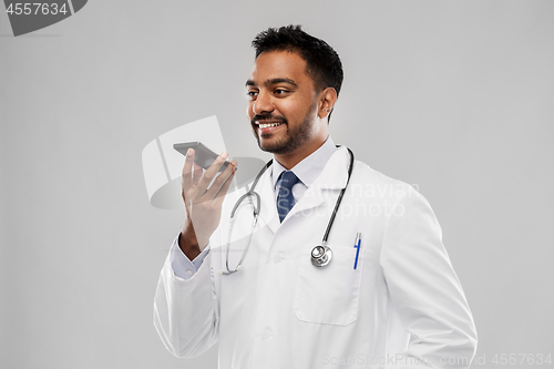 Image of smiling indian male doctor calling on smartphone