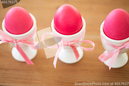 Image of pink colored easter eggs in holders on table