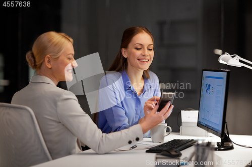 Image of businesswomen with smartphone late at night office