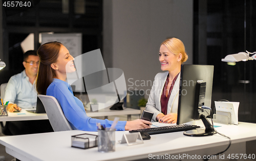 Image of businesswomen with smartphone late at night office