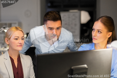 Image of business team with computer working late at office