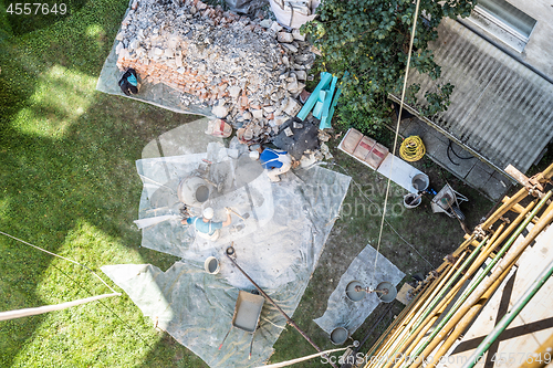 Image of Top view of authentic builder men working with shovel during concrete cement solution mortar preparation in mixer at construction site