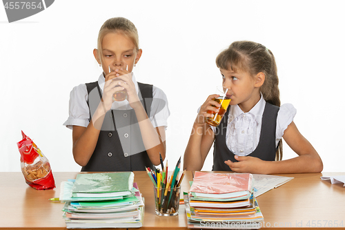 Image of Two school friends drink juice at a table in a school class