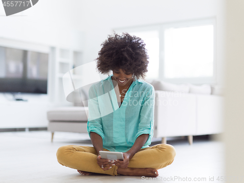 Image of black women using tablet computer on the floor at home