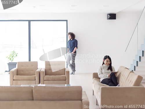 Image of multiethnic couple at home using tablet computers