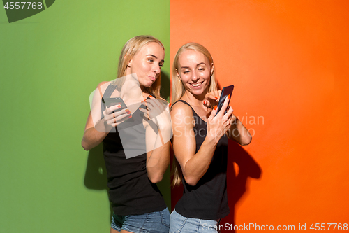 Image of Portrait of a happy smiling casual girls with mobile phones over studio background