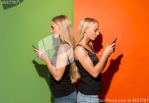 Image of Portrait of a happy smiling casual girls with mobile phones over studio background