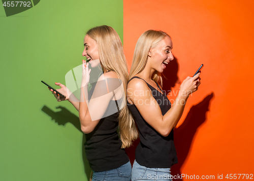 Image of Portrait of a happy smiling casual girls with mobile phones over studio background