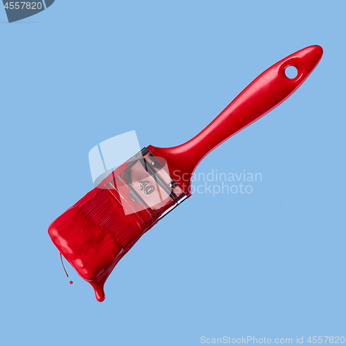 Image of red paintbrush isolated on a blue background