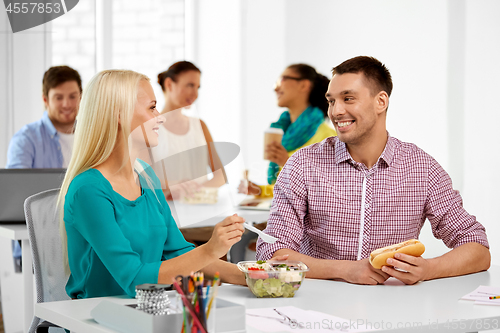 Image of happy colleagues having lunch and eating at office