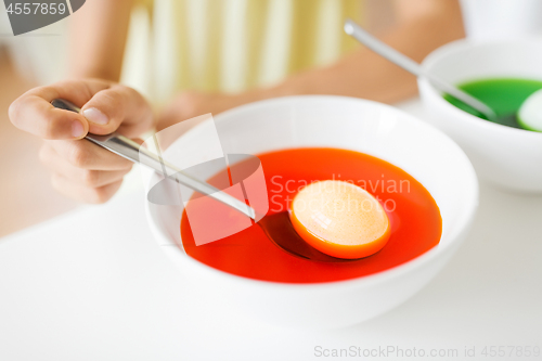 Image of child coloring easter eggs by liquid dye at home