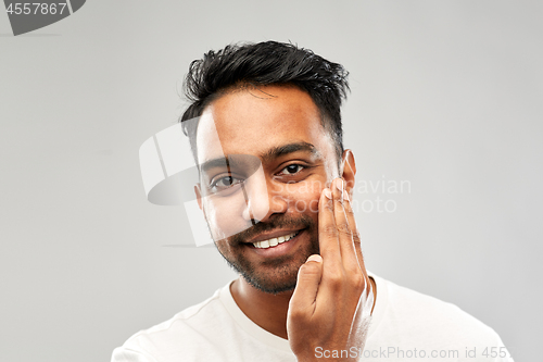 Image of smiling indian man touching his beard