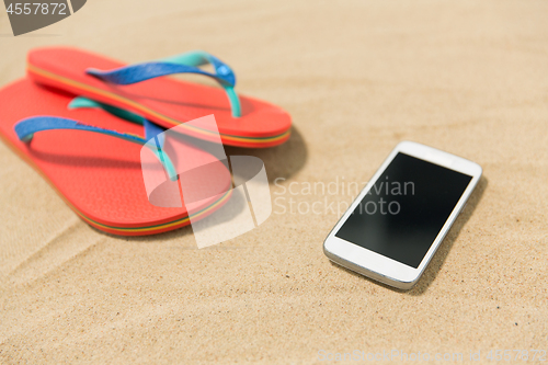 Image of smartphone and flip flops on beach sand