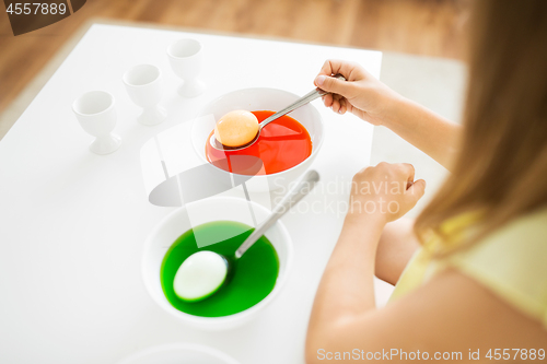 Image of girl coloring easter eggs by liquid dye at home