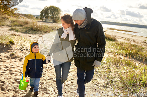 Image of happy family walking along autumn beach