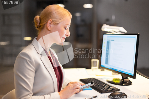 Image of businesswoman with smartphone at night office