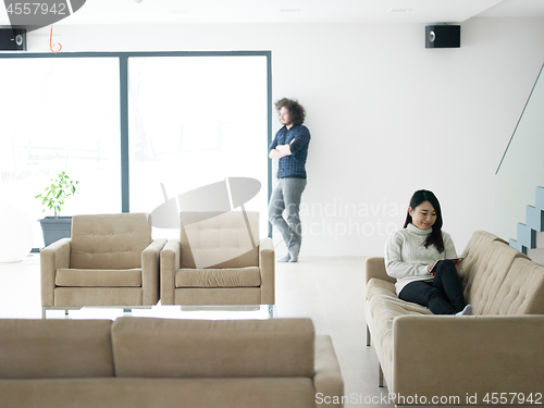 Image of multiethnic couple at home using tablet computers