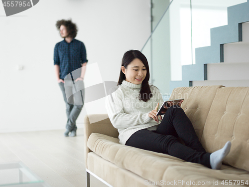 Image of multiethnic couple at home using tablet computers