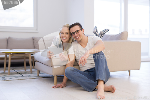 Image of couple relaxing at  home with tablet computers