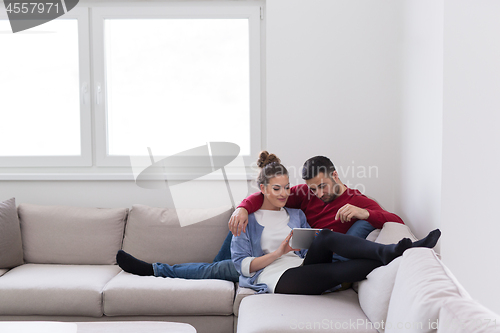 Image of couple relaxing at  home with tablet computers