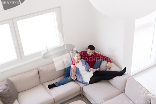 Image of couple relaxing at  home with tablet computers