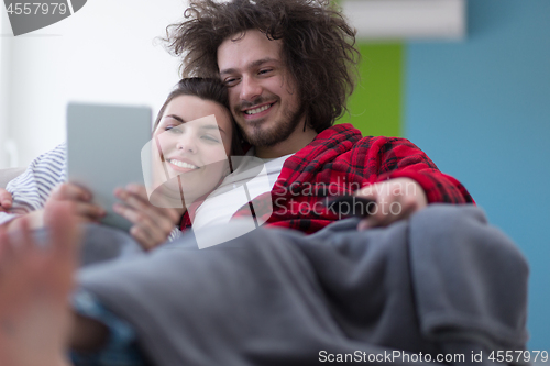 Image of couple relaxing at  home with tablet computers