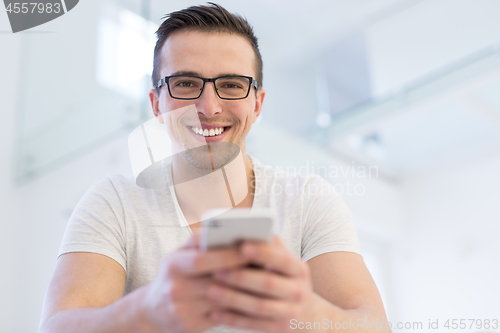 Image of young man using a mobile phone  at home