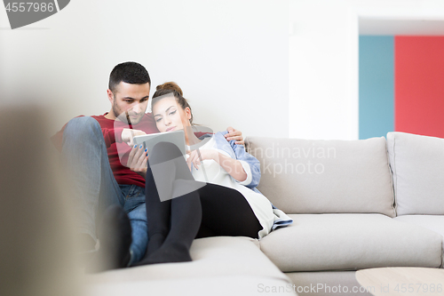 Image of couple relaxing at  home with tablet computers