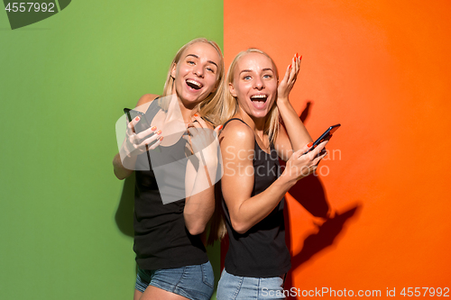 Image of Portrait of a happy smiling casual girls with mobile phones over studio background