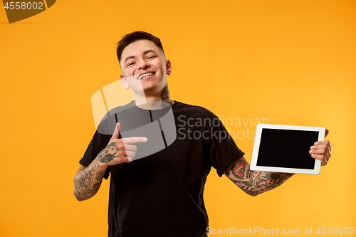 Image of Portrait of a confident casual man showing blank screen of laptop