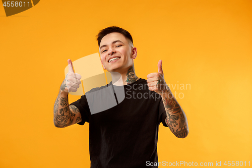 Image of The happy businessman standing and smiling against orange background.