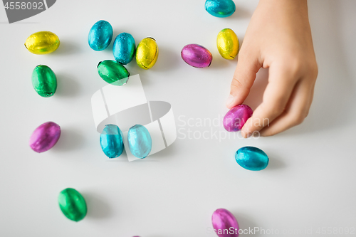 Image of hand of child with chocolate easter eggs in foil