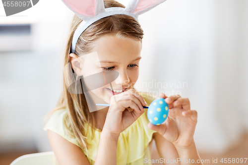 Image of happy girl coloring easter eggs at home