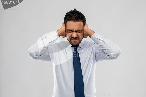 Image of indian businessman covering ears with hands