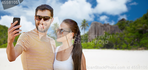 Image of happy couple taking selfie by smartphone on beach